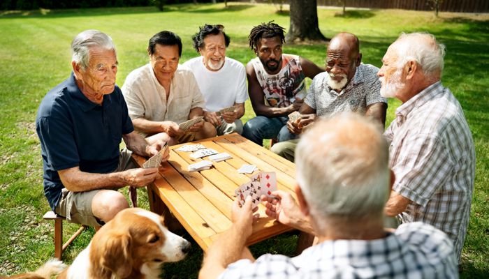 A group of men sharing a card game around a picnic table outdoors